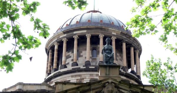 A rotund building top with a romanized bronze statue in front, the Supreme Court of Victoria